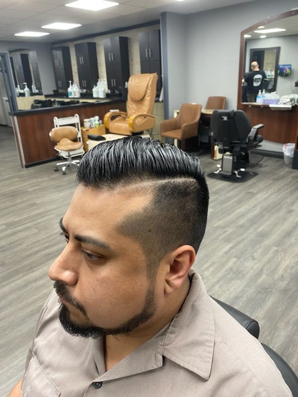 A man with a beard is getting his hair cut at a barber shop
