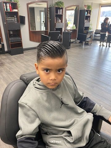 A young boy is sitting in a chair in a barber shop.