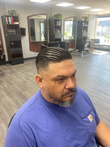 A man with a beard is getting his hair cut at a barber shop.