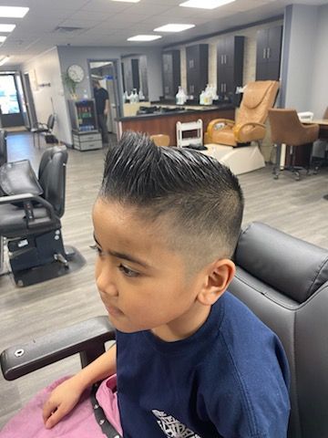 A young boy is sitting in a chair in a barber shop.