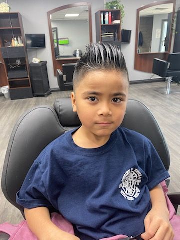 A young boy is sitting in a chair in a barber shop.