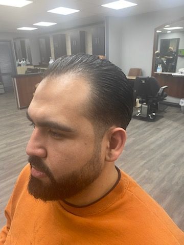 A man with a beard is getting his hair cut at a barber shop.