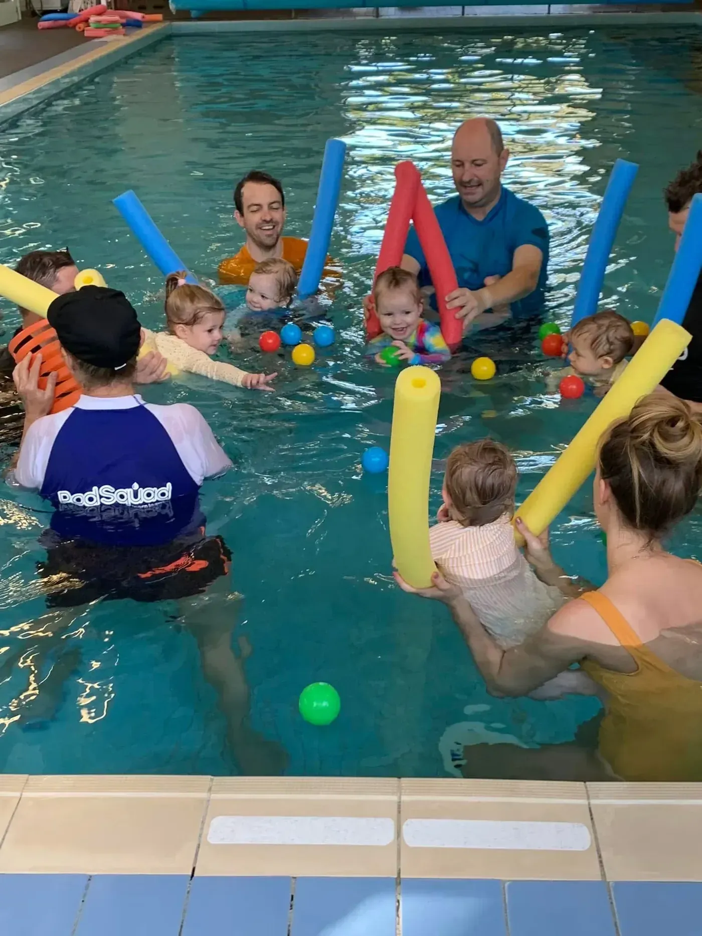 Fathers holding their babies in a Pod Squad class, with an instructor guiding the group