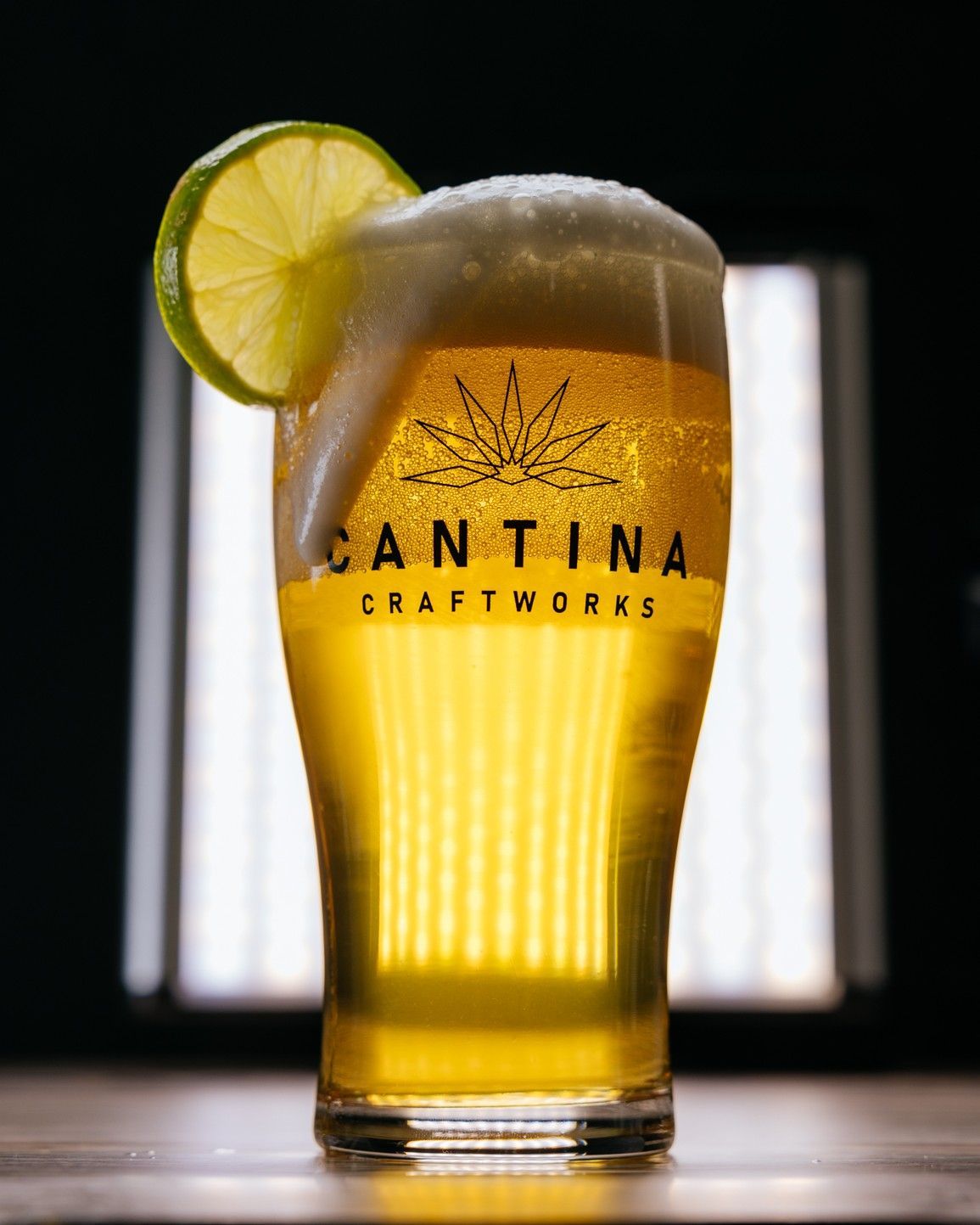 A glass of cantina craftworks beer with a slice of lime on top