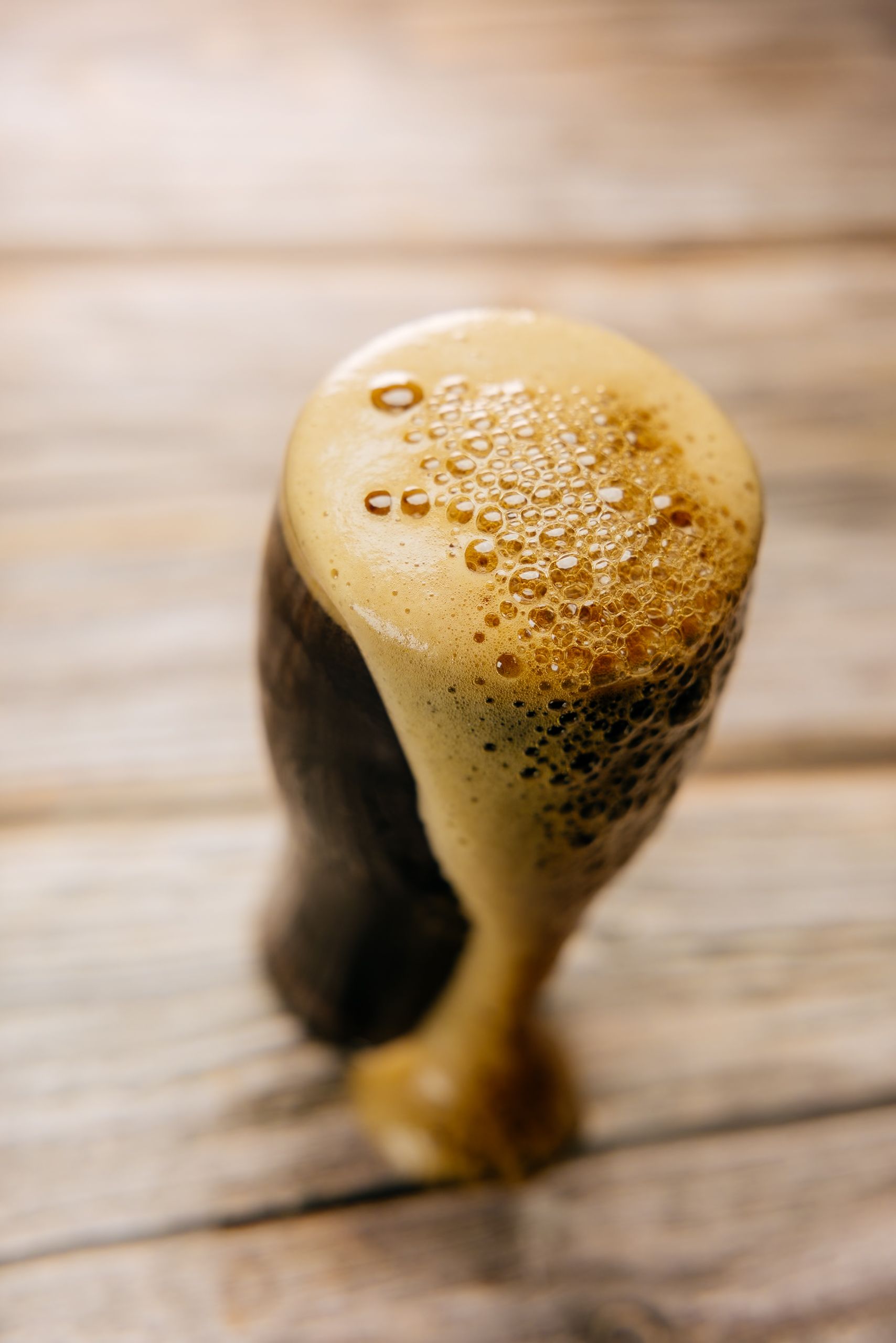 A close up of a glass of beer on a wooden table.