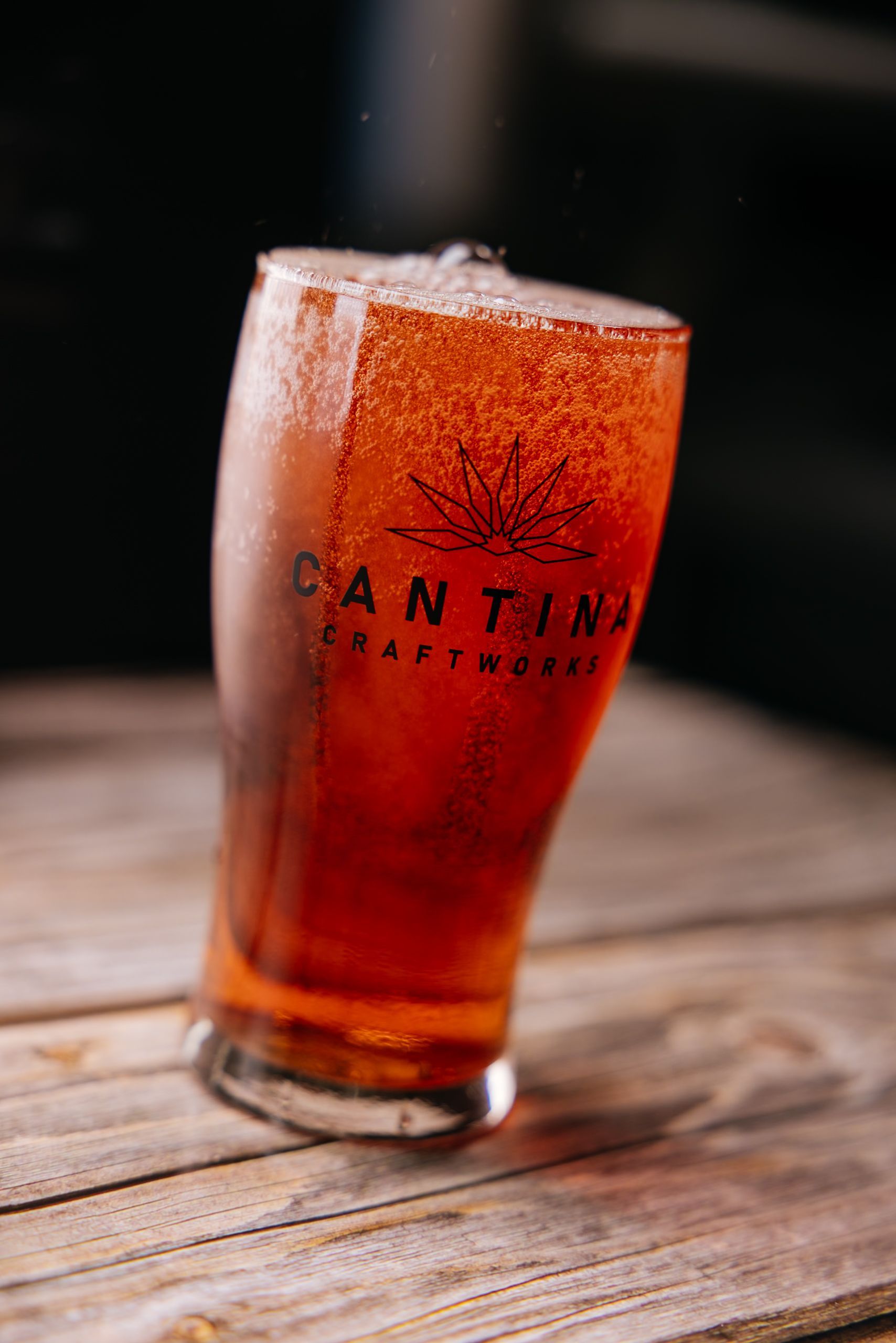 A glass of beer is sitting on a wooden table.