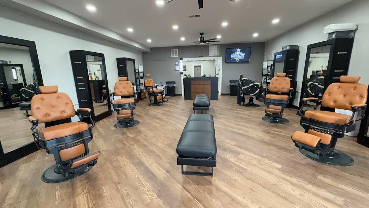 Modern barber shop with leather chairs, mirrors, and a long central bench on wood flooring.