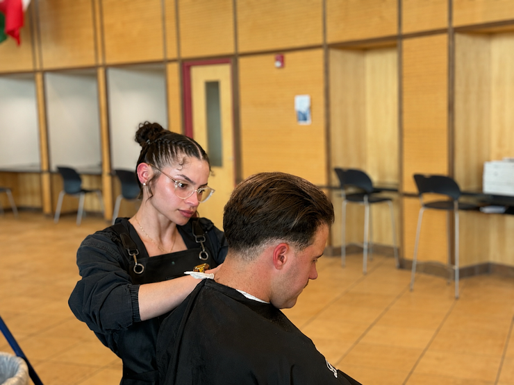 Hairdresser styling a seated client in a bright salon with mirrors and chairs