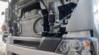 Truck front with hood open, showing engine components and headlight.