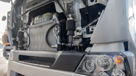 Truck front with hood open, showing engine components and headlight.