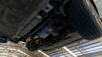 Underside of a vehicle on a lift in a garage, showing wheels and chassis components