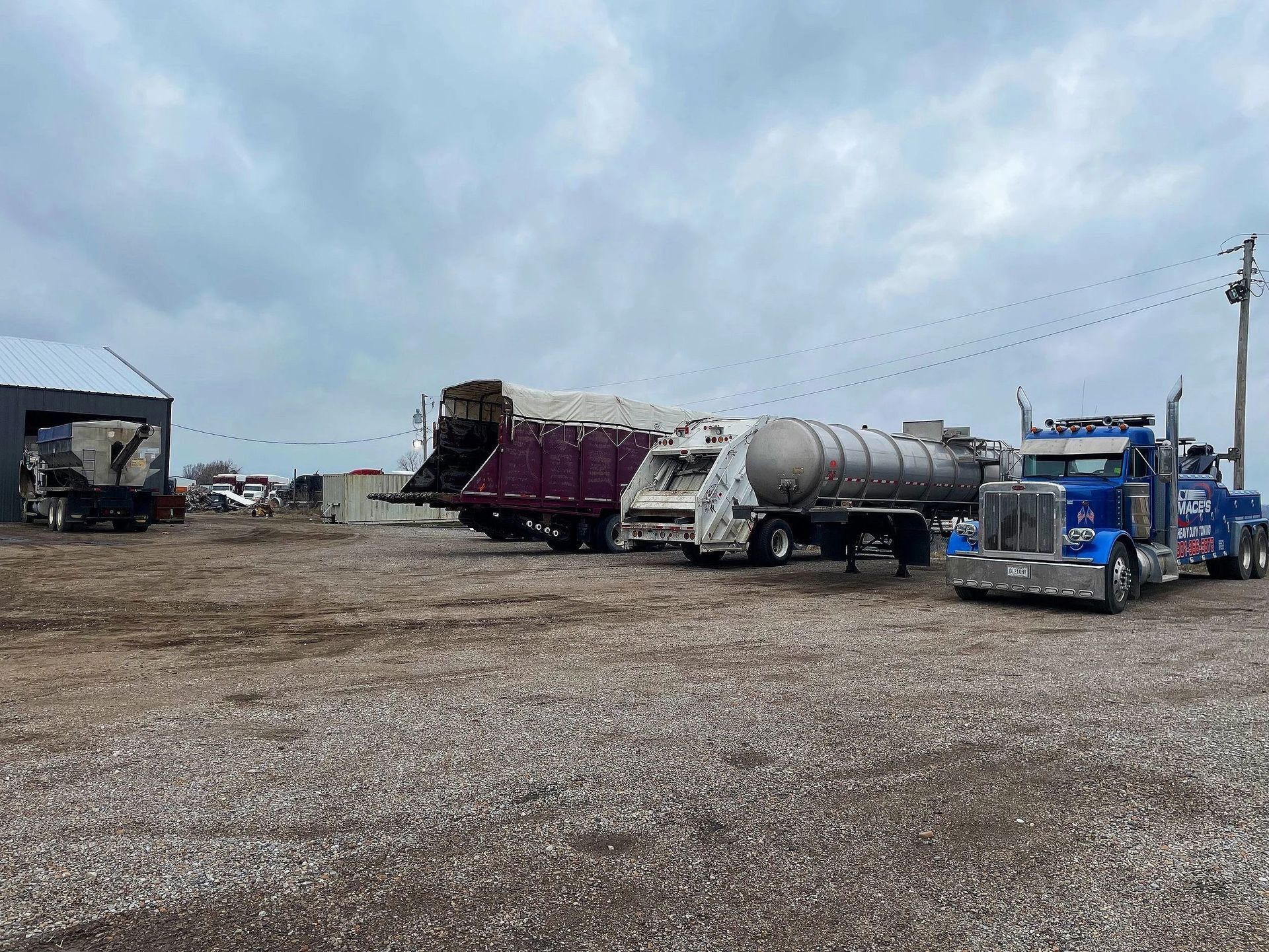 Industrial yard with parked semi trucks and trailers under a cloudy sky