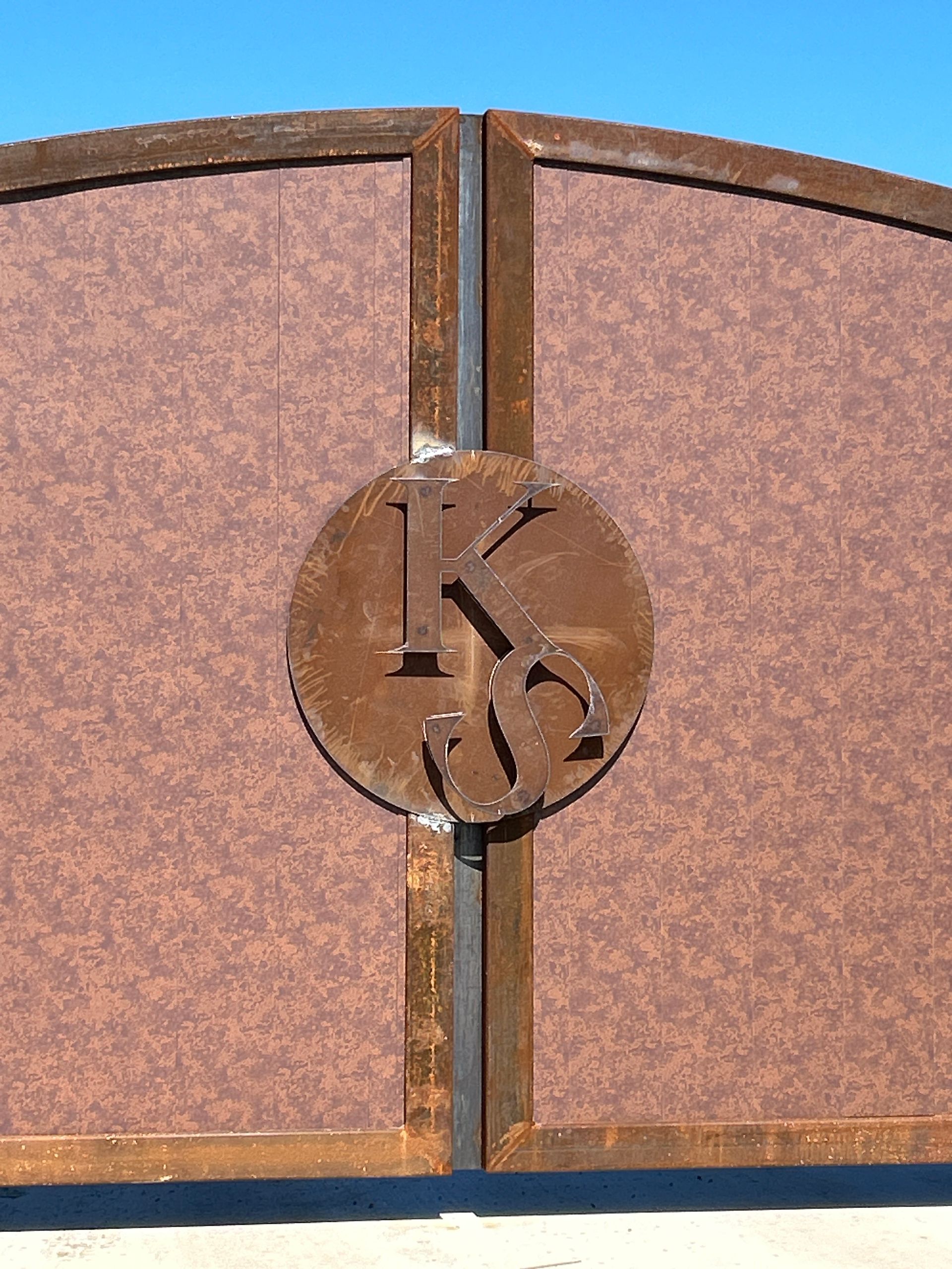 Close-up of a bronze metal gate with a circular decorative emblem at the center.