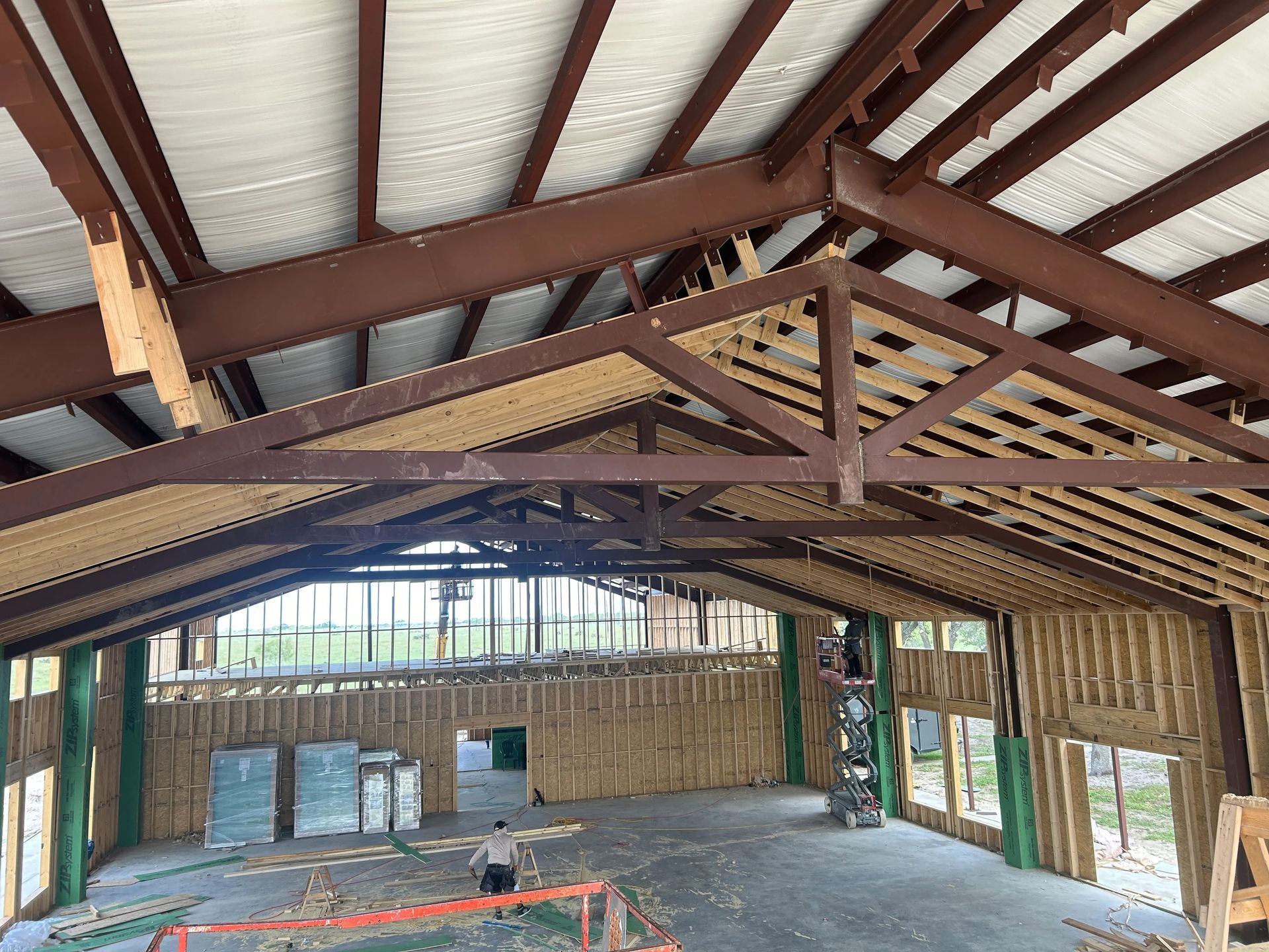 Interior of a rustic wooden building under construction, with exposed rafters and corrugated metal roof.