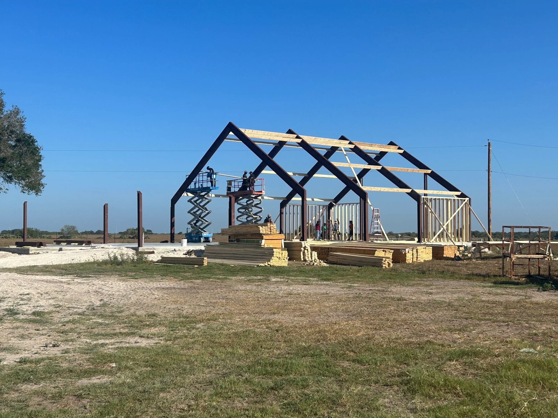 Partially built wooden frame structure on a dry lot under a clear blue sky