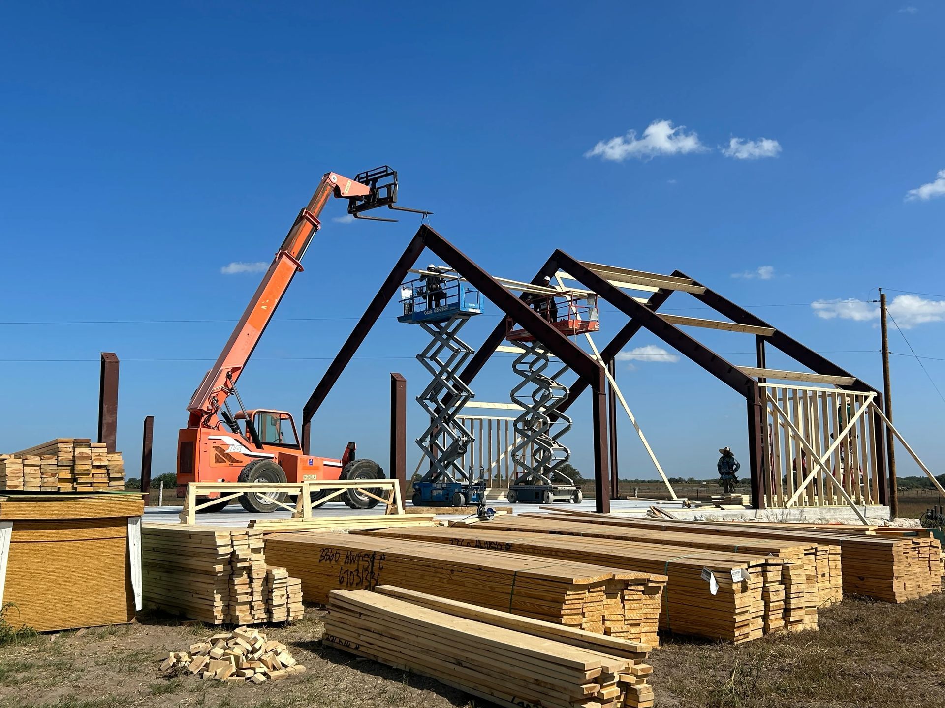 Construction site with crane lifting steel beams for a building frame under a clear blue sky