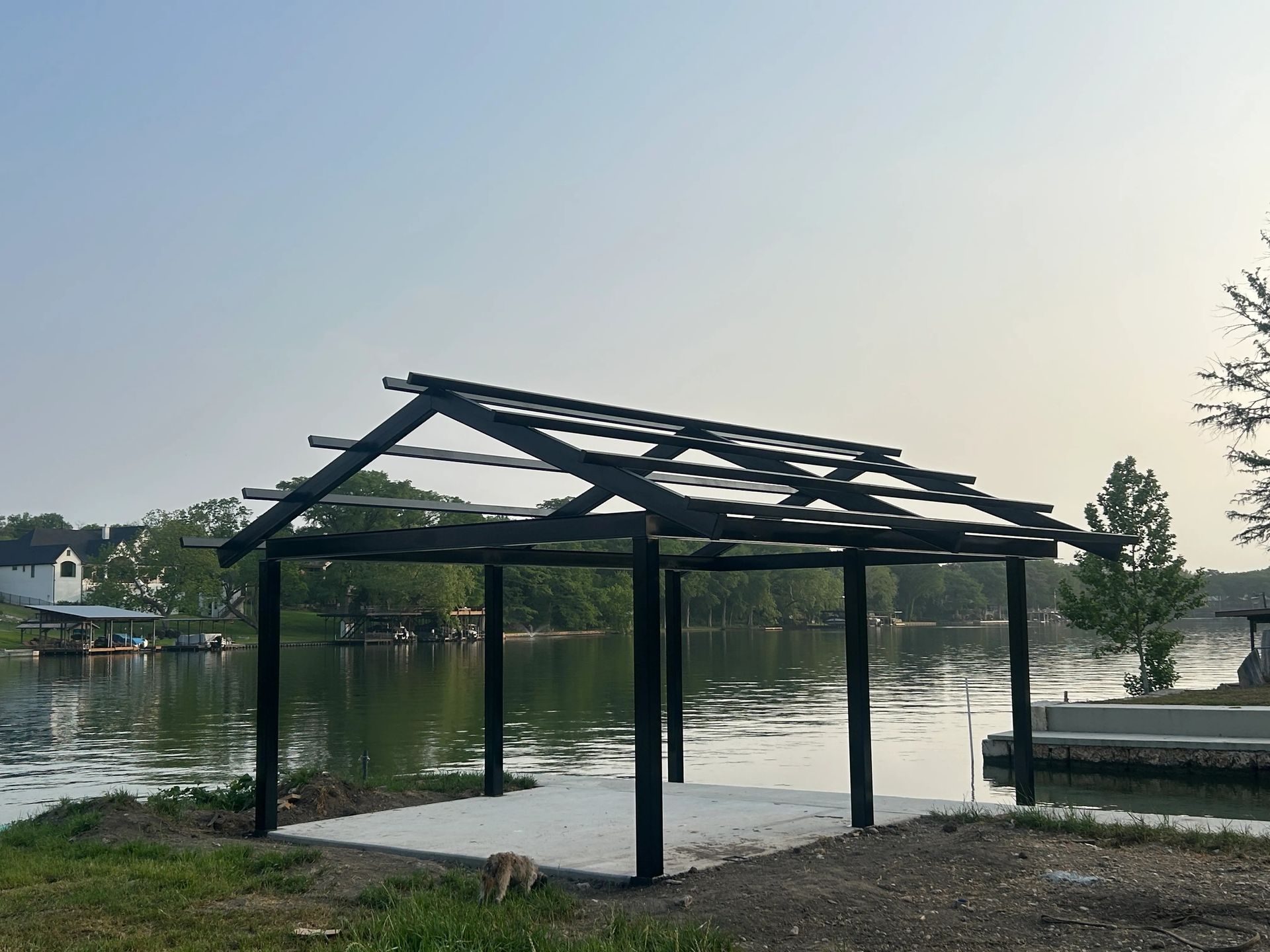 Partially built wooden dock shelter by a calm lake at sunset