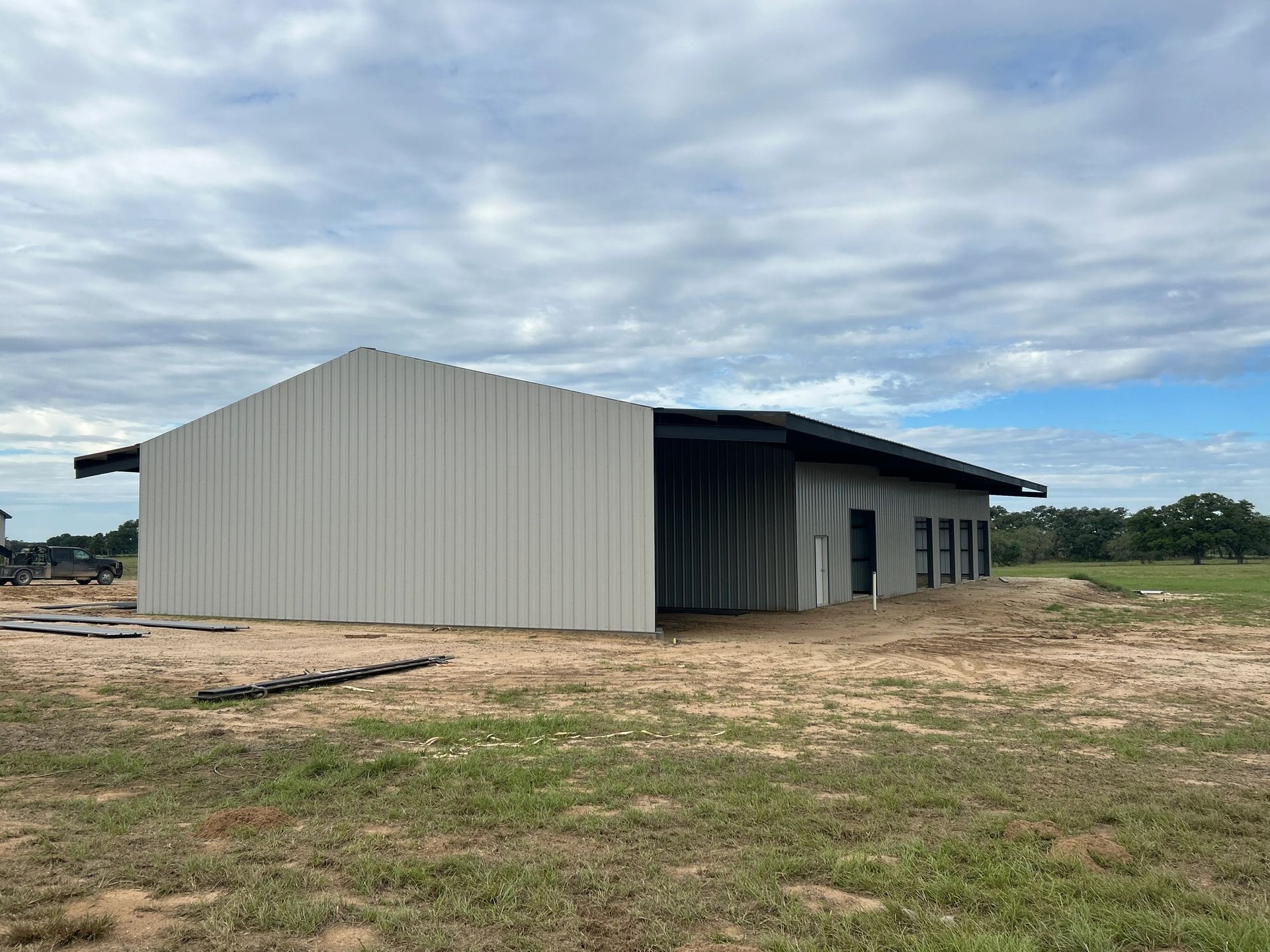 Partially built metal shed on a dirt lot under a cloudy sky