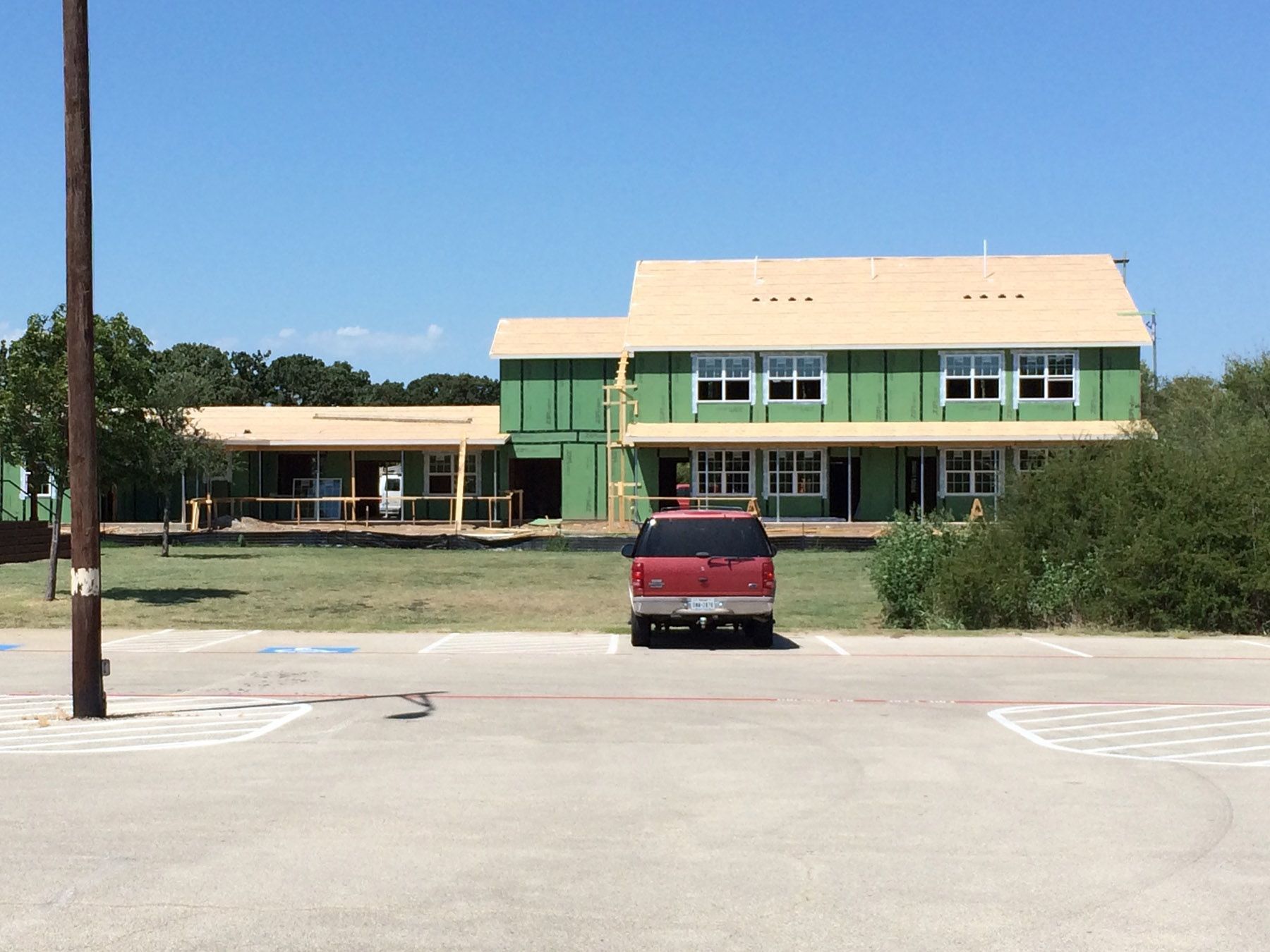 A red truck is parked in front of a house under construction