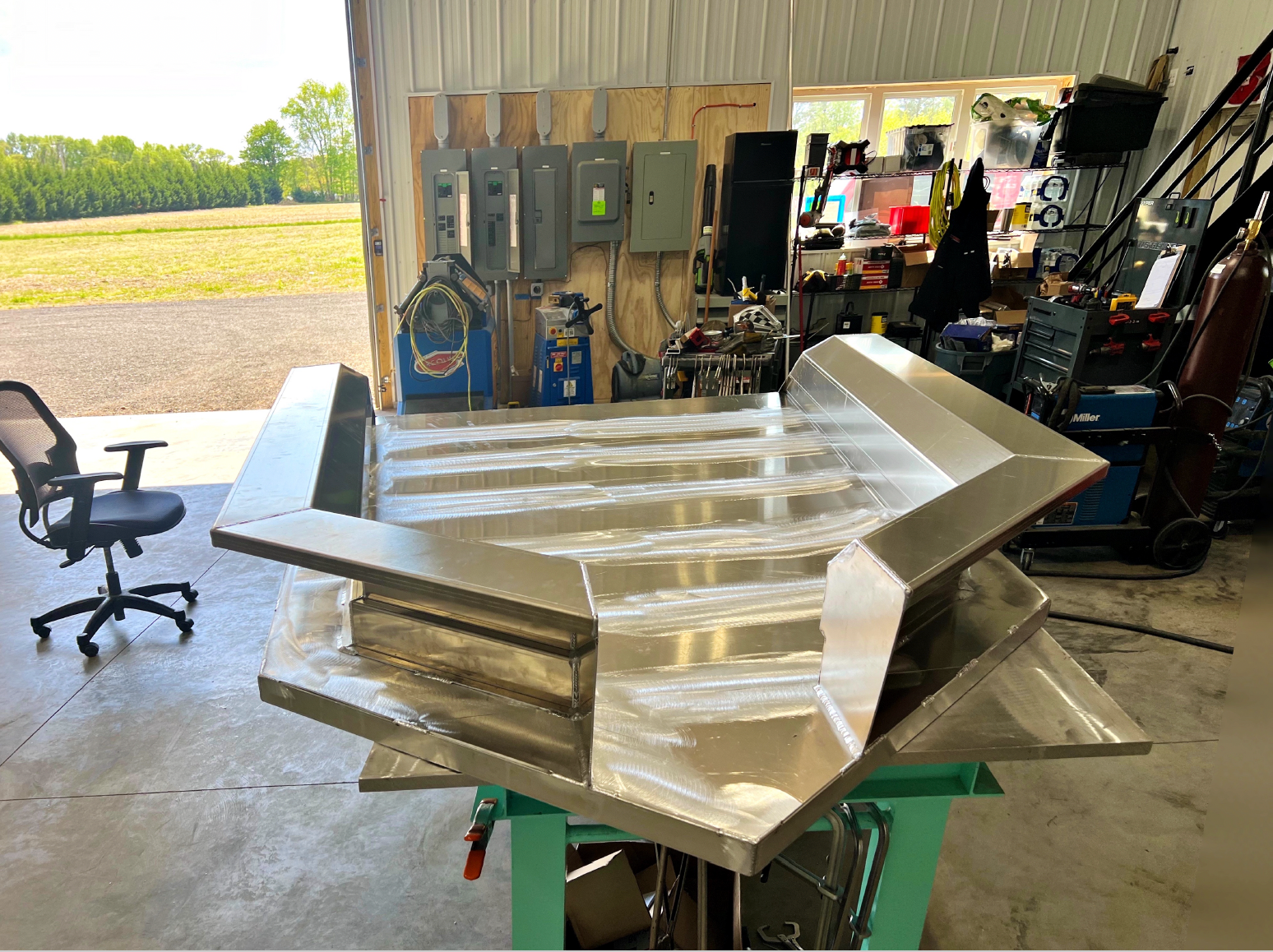 A stainless steel boat is sitting in the fabrication shop.