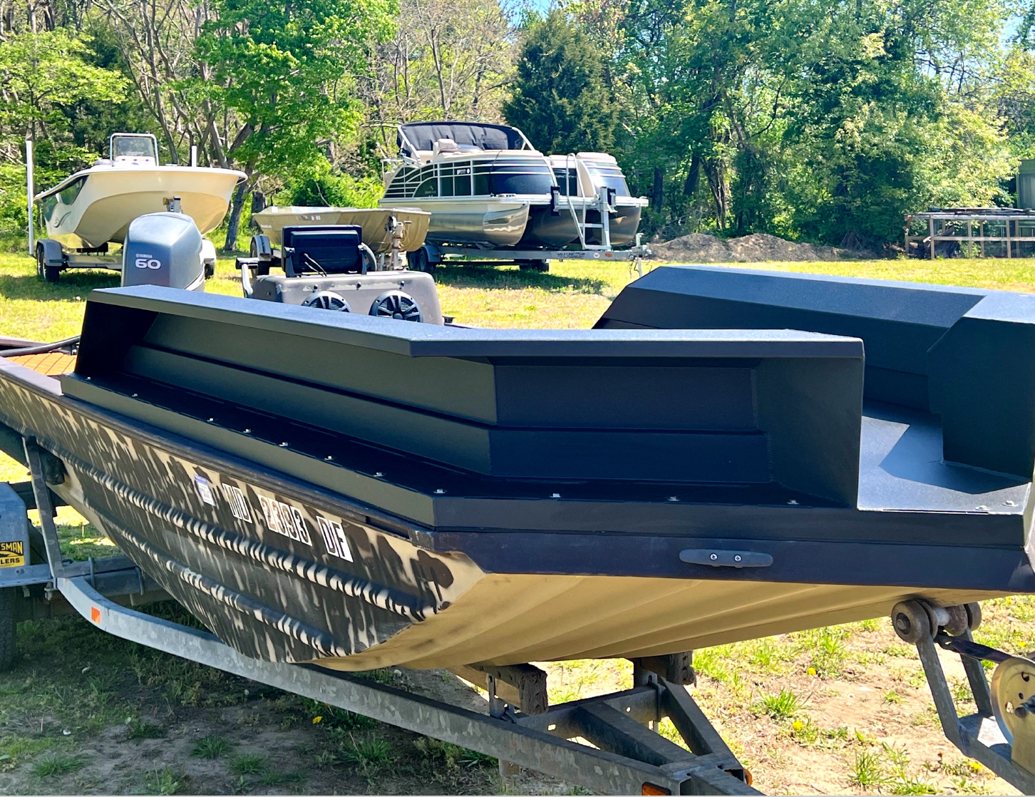 A boat is sitting on a trailer in a field.