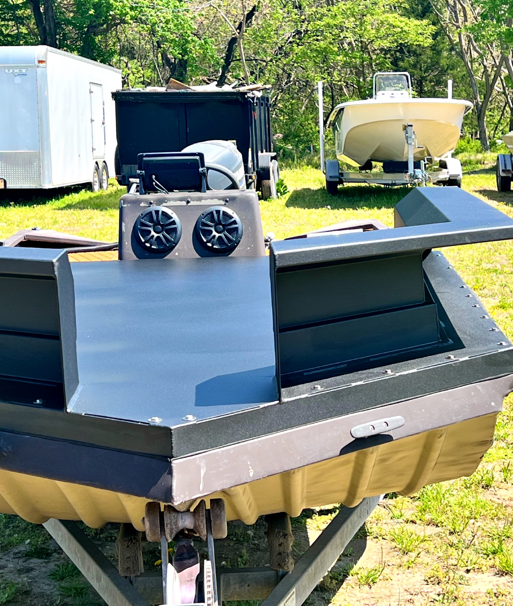 A boat is sitting on a trailer in a grassy field.