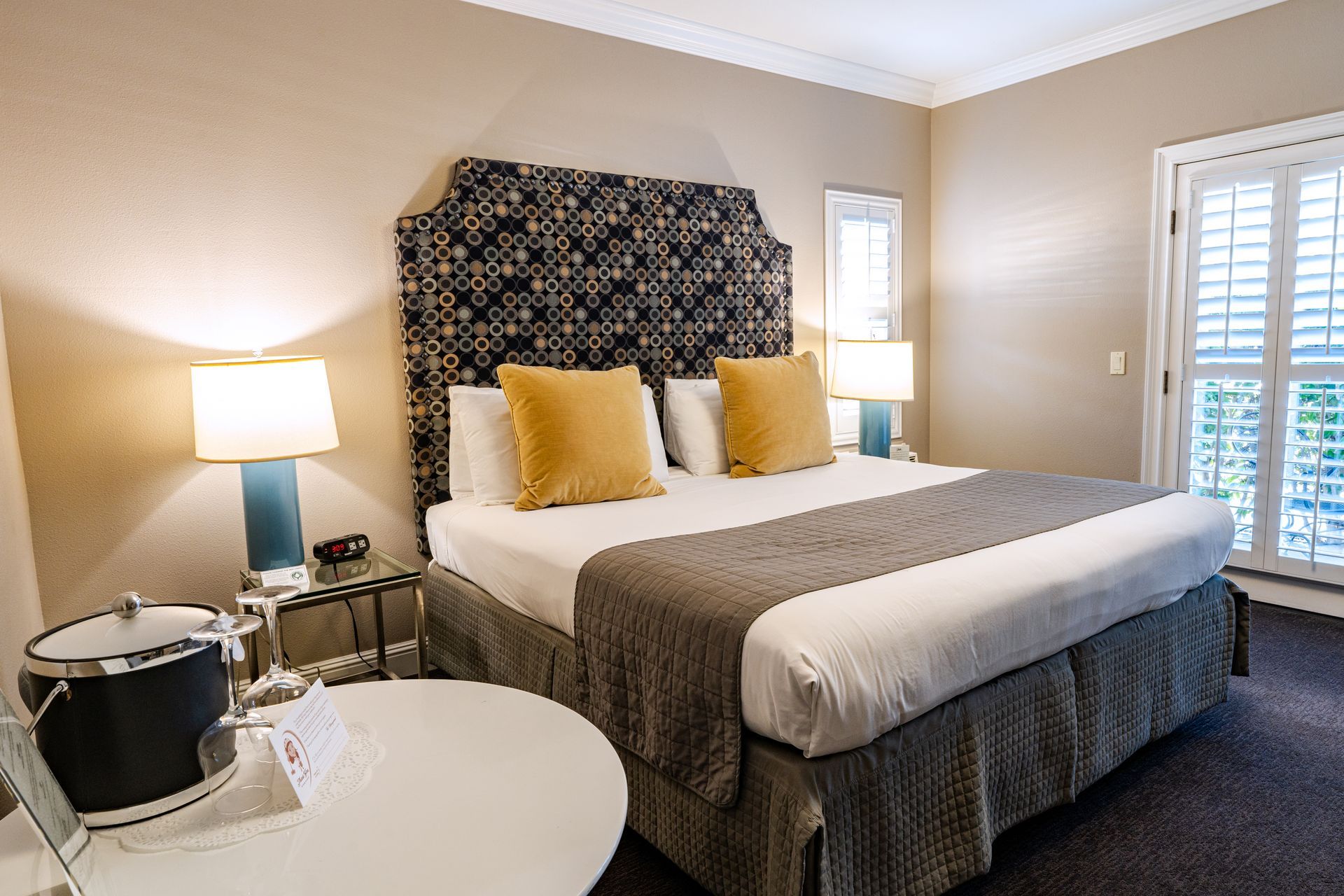 Bedroom with a king-size bed, featuring a patterned headboard, yellow pillows, and blue lamps.