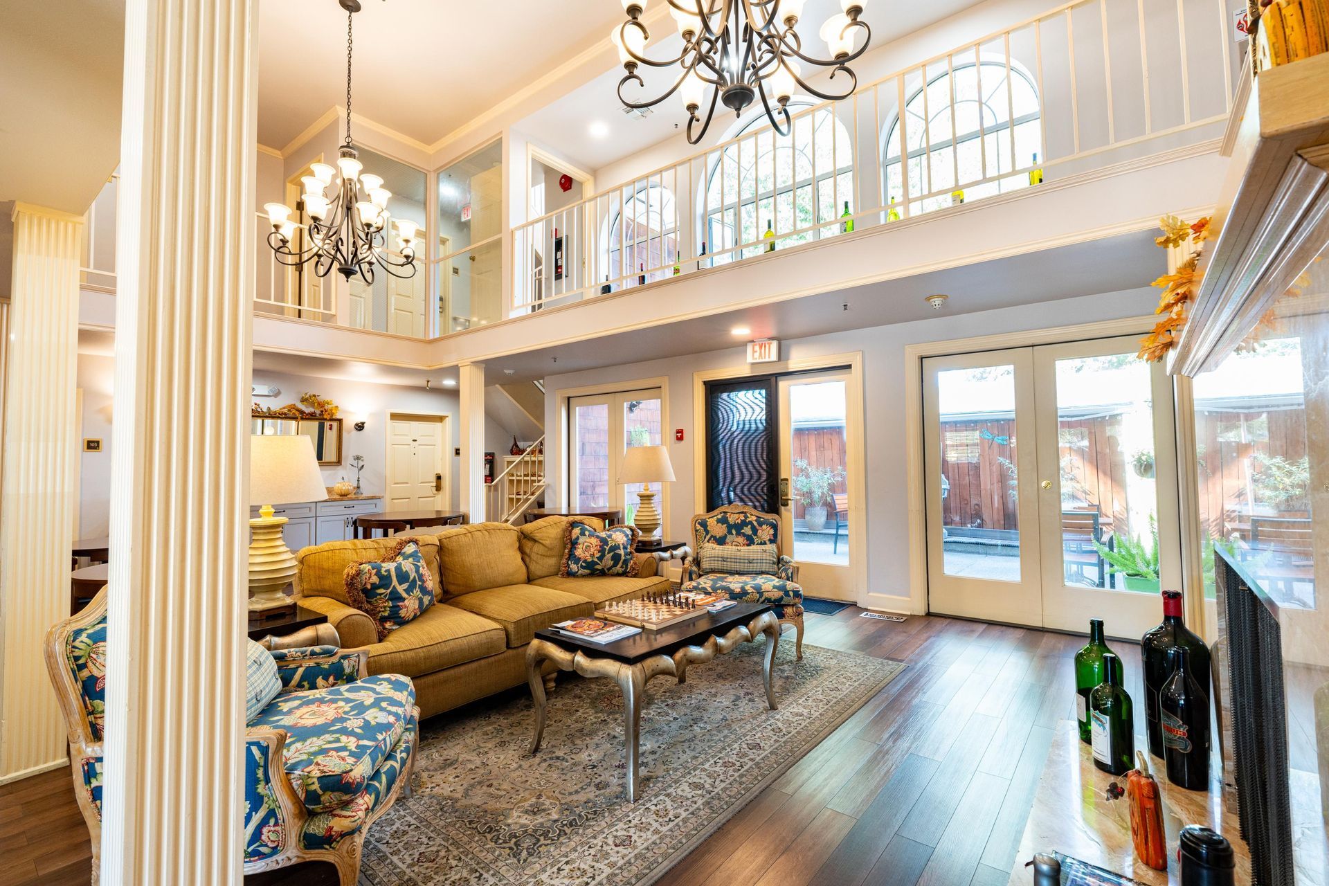 Living room with high ceilings, chandelier, sofa, and French doors leading to an outdoor area.