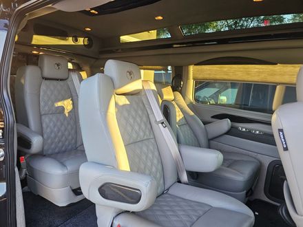 Interior of a van with gray leather seats and overhead lighting.