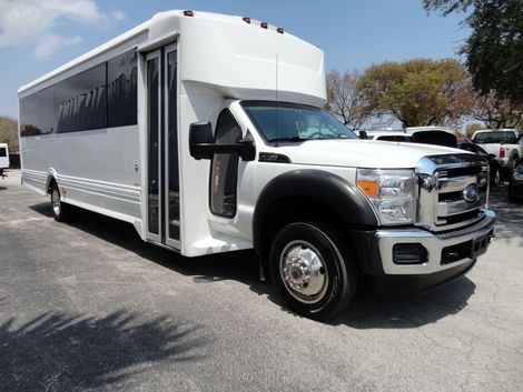 White shuttle bus parked outside on a sunny day.