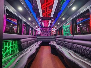 Interior of a party bus with leather seating, neon lights, and a dance floor.