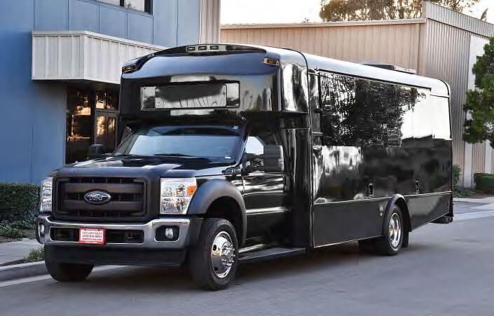 Black party bus parked on a city street in front of a building.