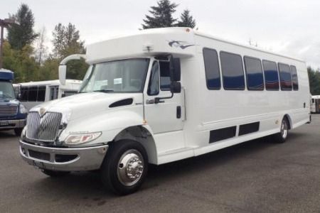 White passenger bus parked outside, with tinted windows and chrome accents.