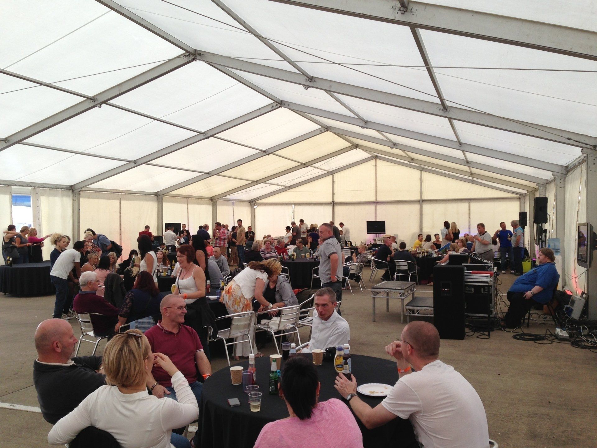 People gathered inside a large white tent, socializing at tables.