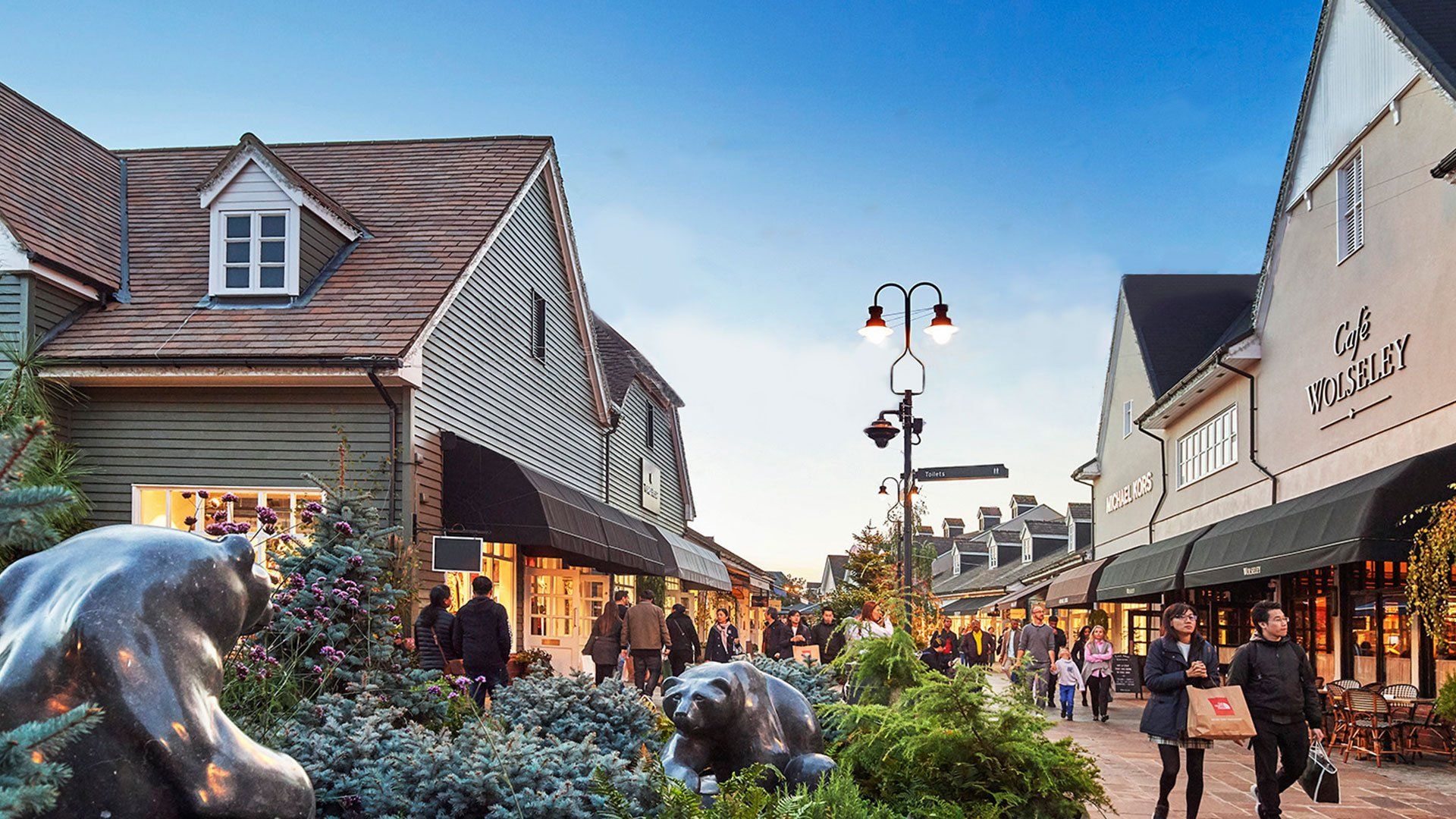 Shopping street with shops, pedestrians, and decorative bear statues.