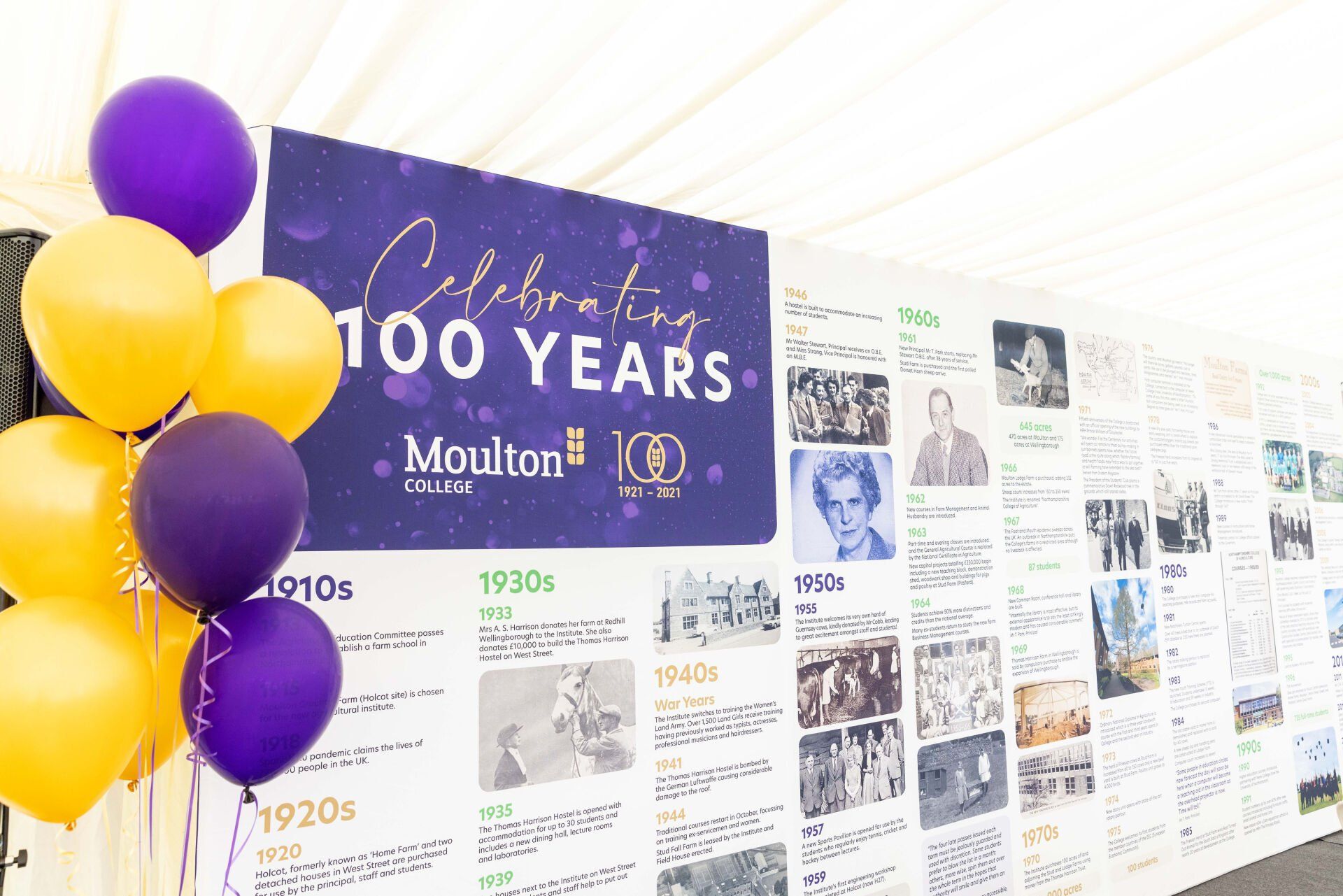 A banner celebrating 100 years with balloons, timeline, and photographs, featuring purple and gold.