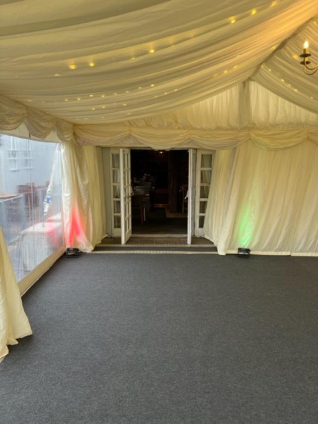 Inside a white tent, dark gray carpet, open doors, and green/red lights.