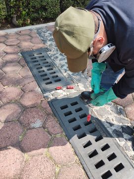 Un hombre está trabajando en una tapa de alcantarilla en una acera.