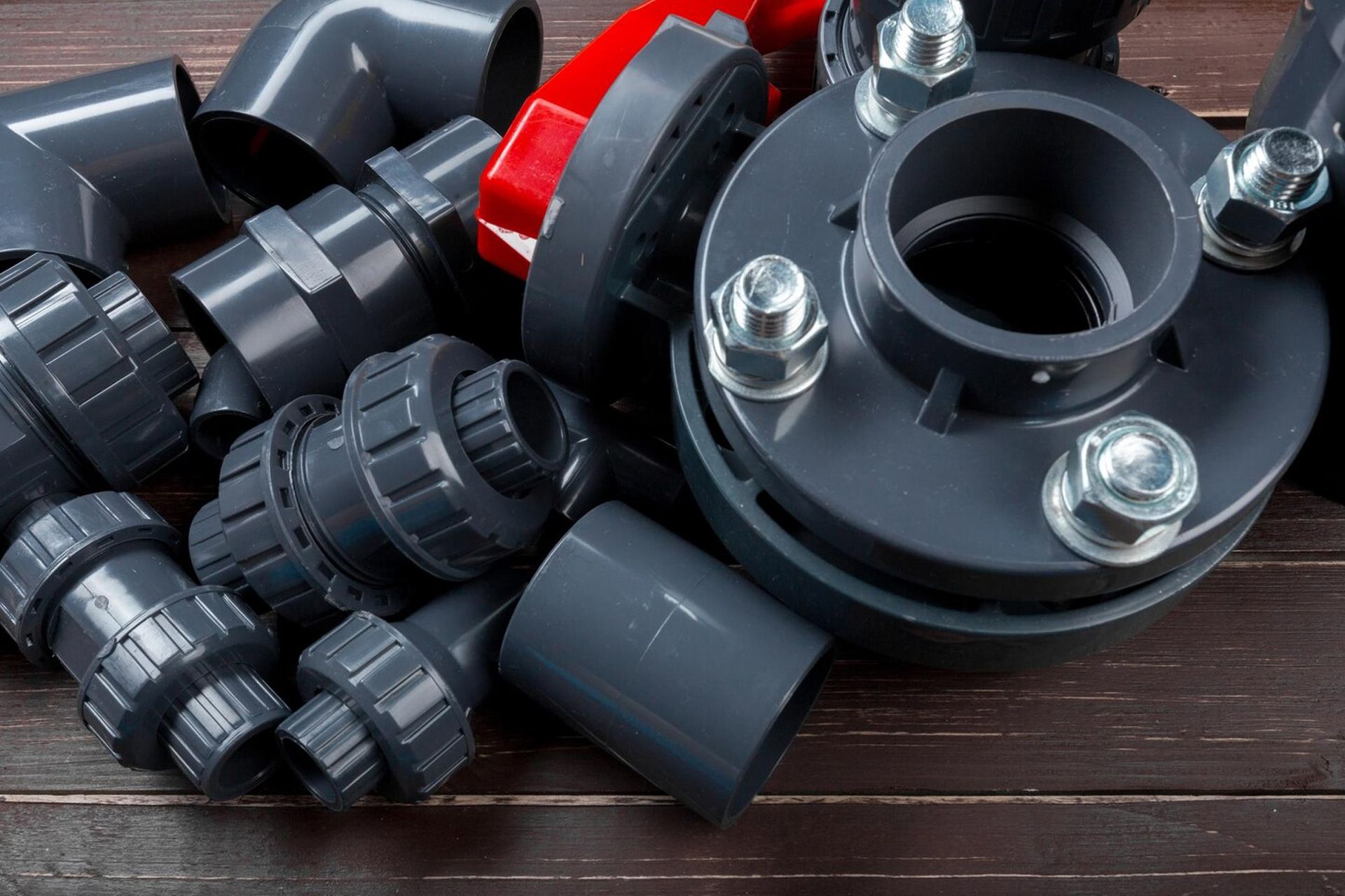 Assorted gray PVC pipe fittings and valves on a wooden surface.