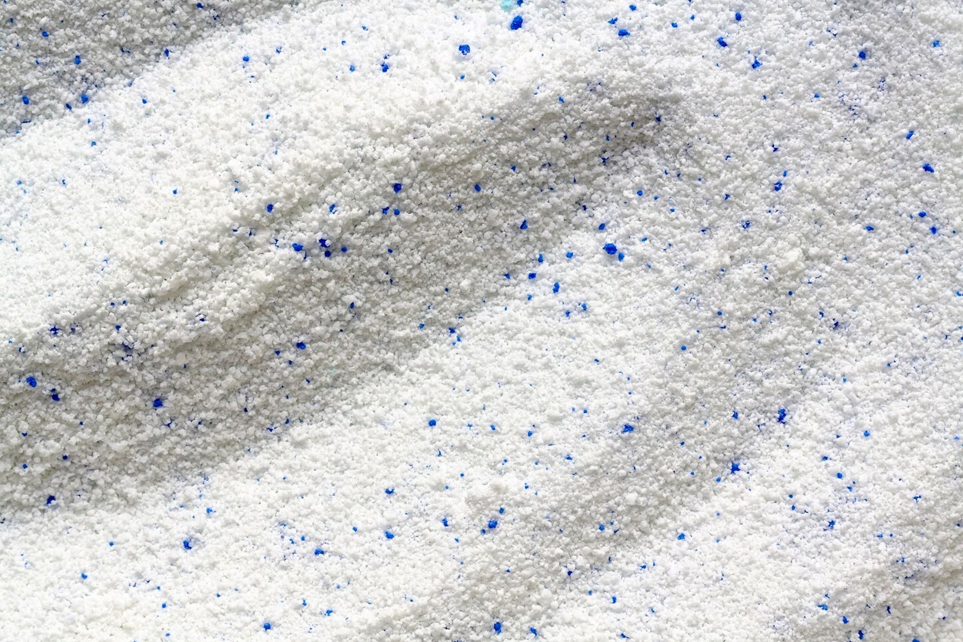 White laundry detergent with scattered blue granules.