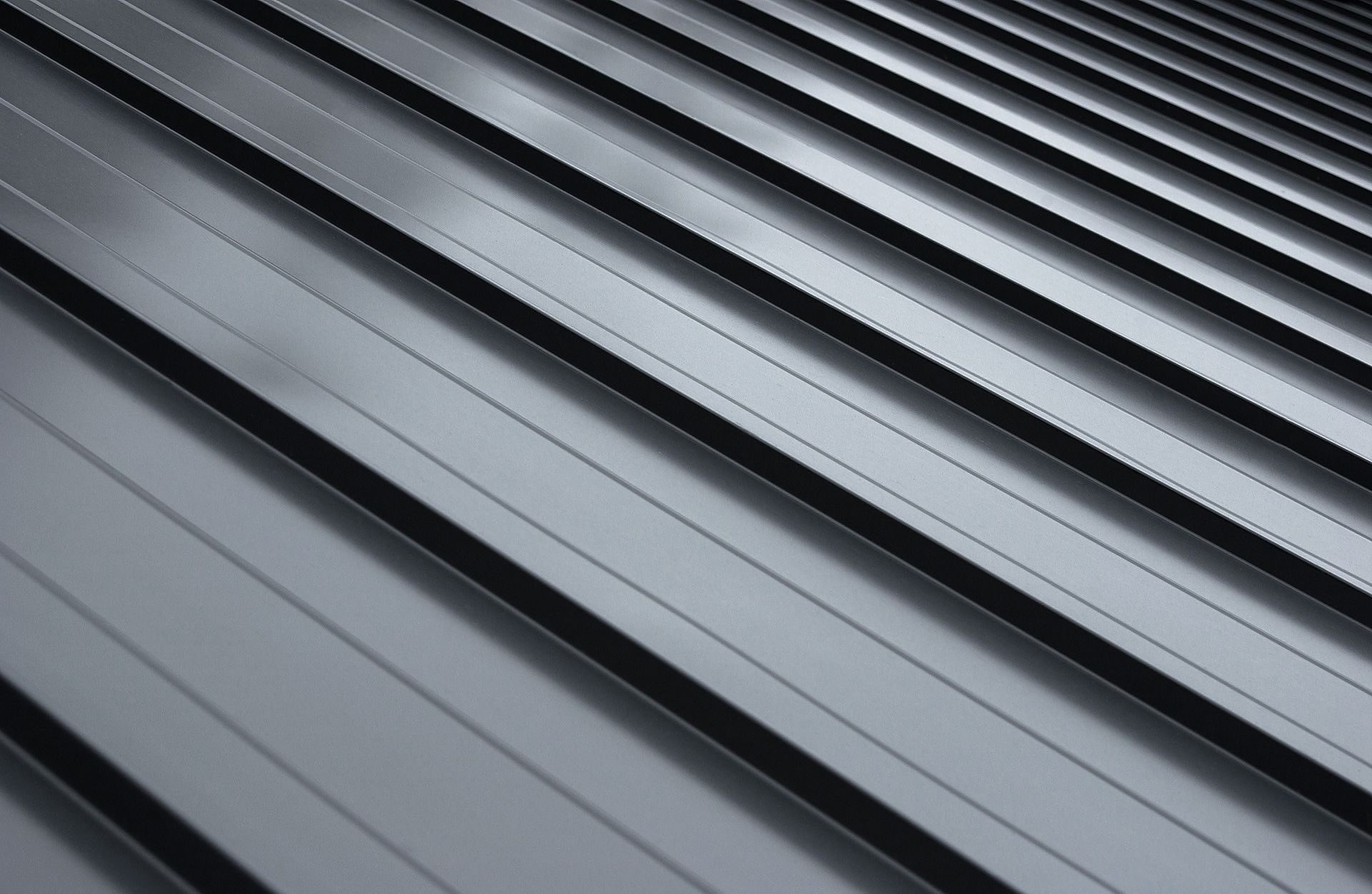 Close-up of a sleek, dark gray metal roof with parallel ridges and subtle light reflections.