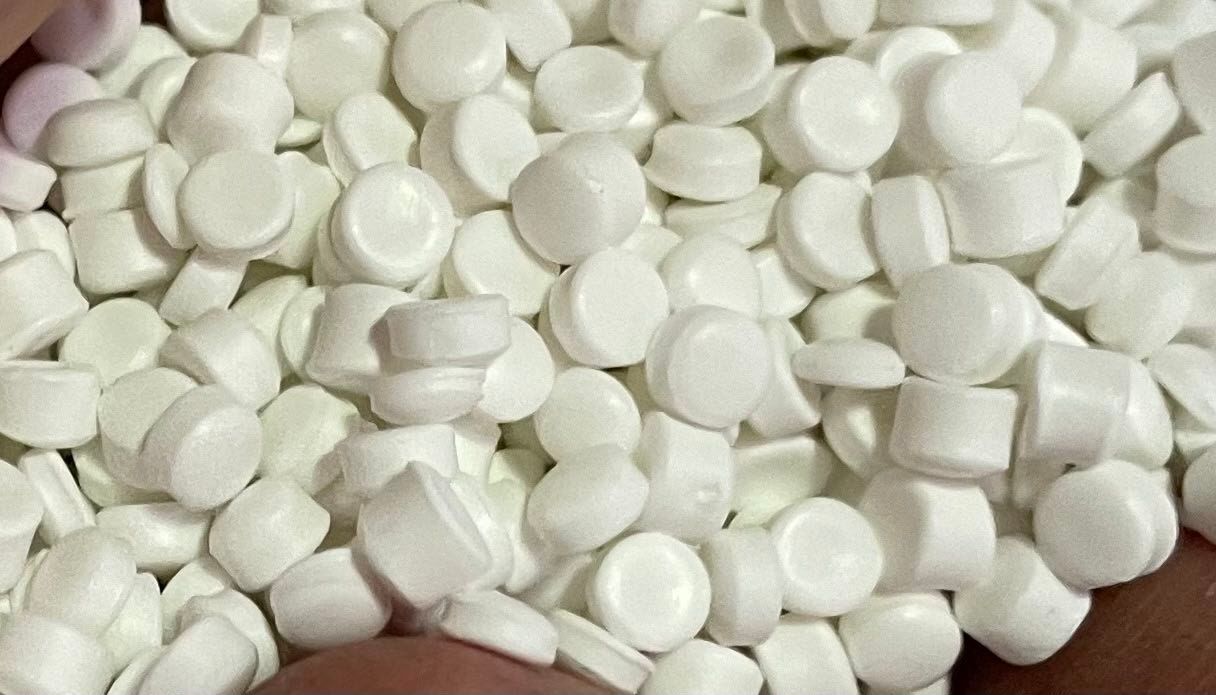 Un tas de petits comprimés blancs, ronds et en forme de disque.