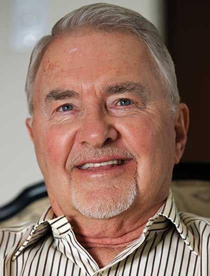 Smiling man in a striped shirt, close-up portrait against a dark background