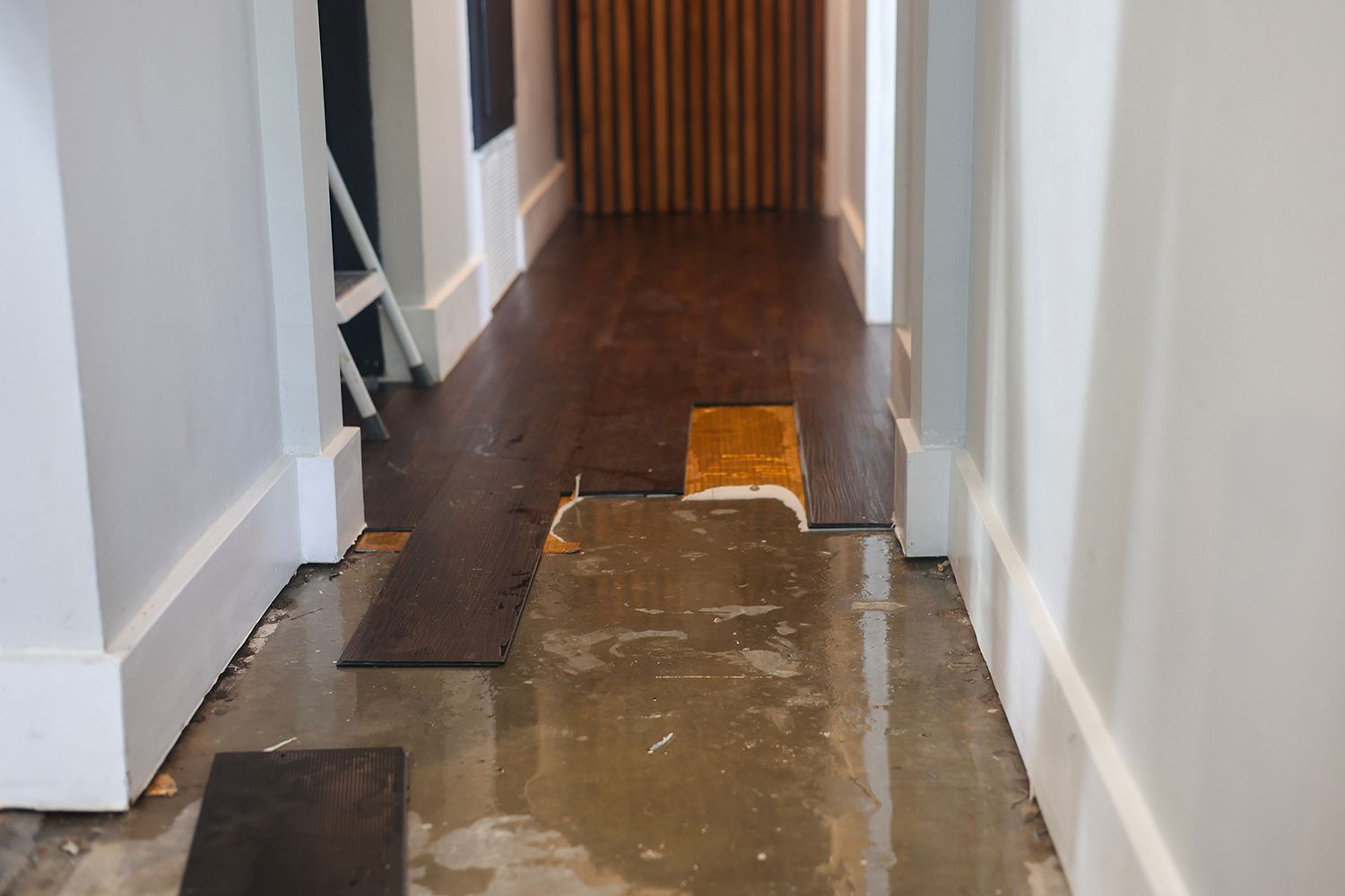 Water-damaged hallway floor with warped wood planks.