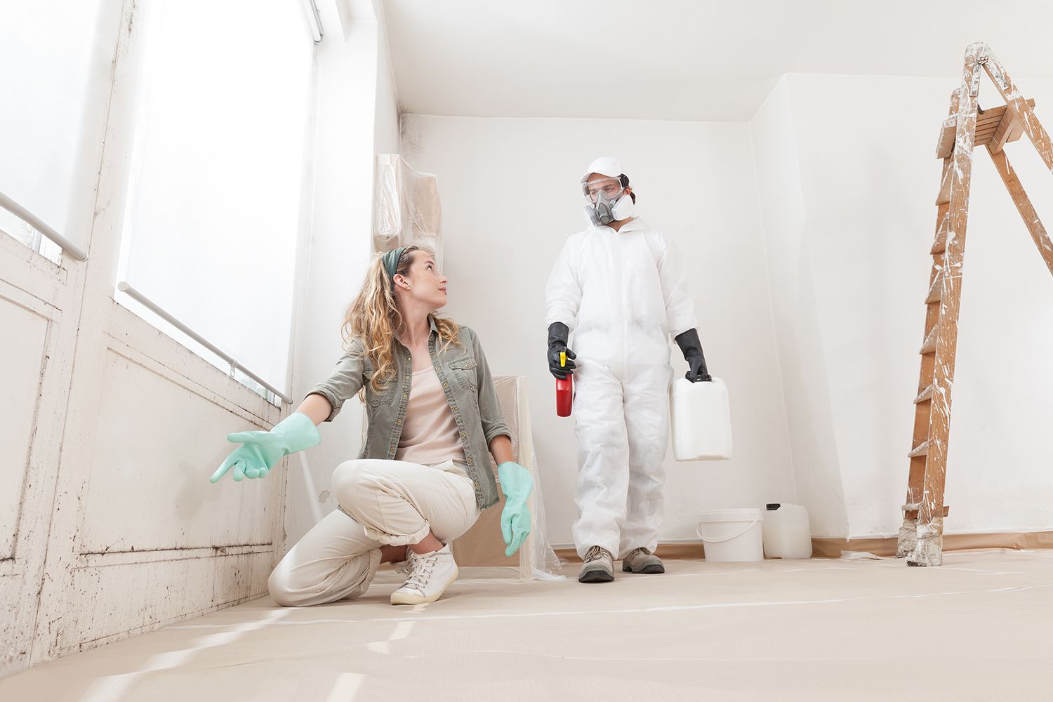 A concerned woman shows a mold problem to a professional for remediation treatment. A concerned woman shows a mold problem to a professional for remediation treatment.