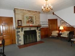 Living room with stone fireplace, chandelier, brown furniture, and a carpeted floor