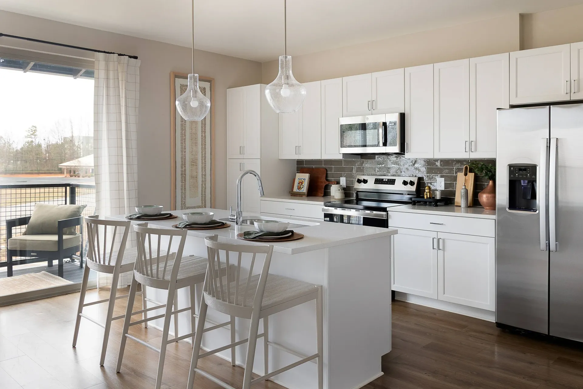 Modern kitchen with white cabinets, stainless steel appliances, and an island with bar stools.