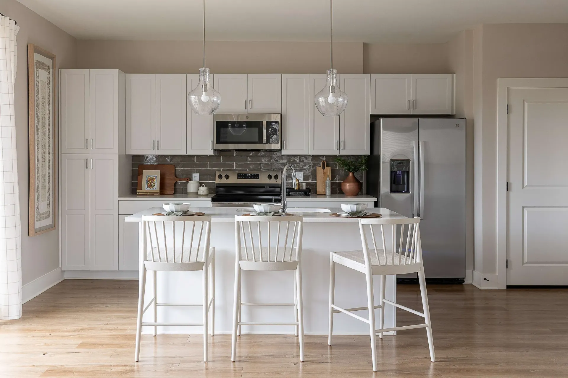 Modern kitchen with white cabinets, stainless steel appliances, and a large island with bar stools.