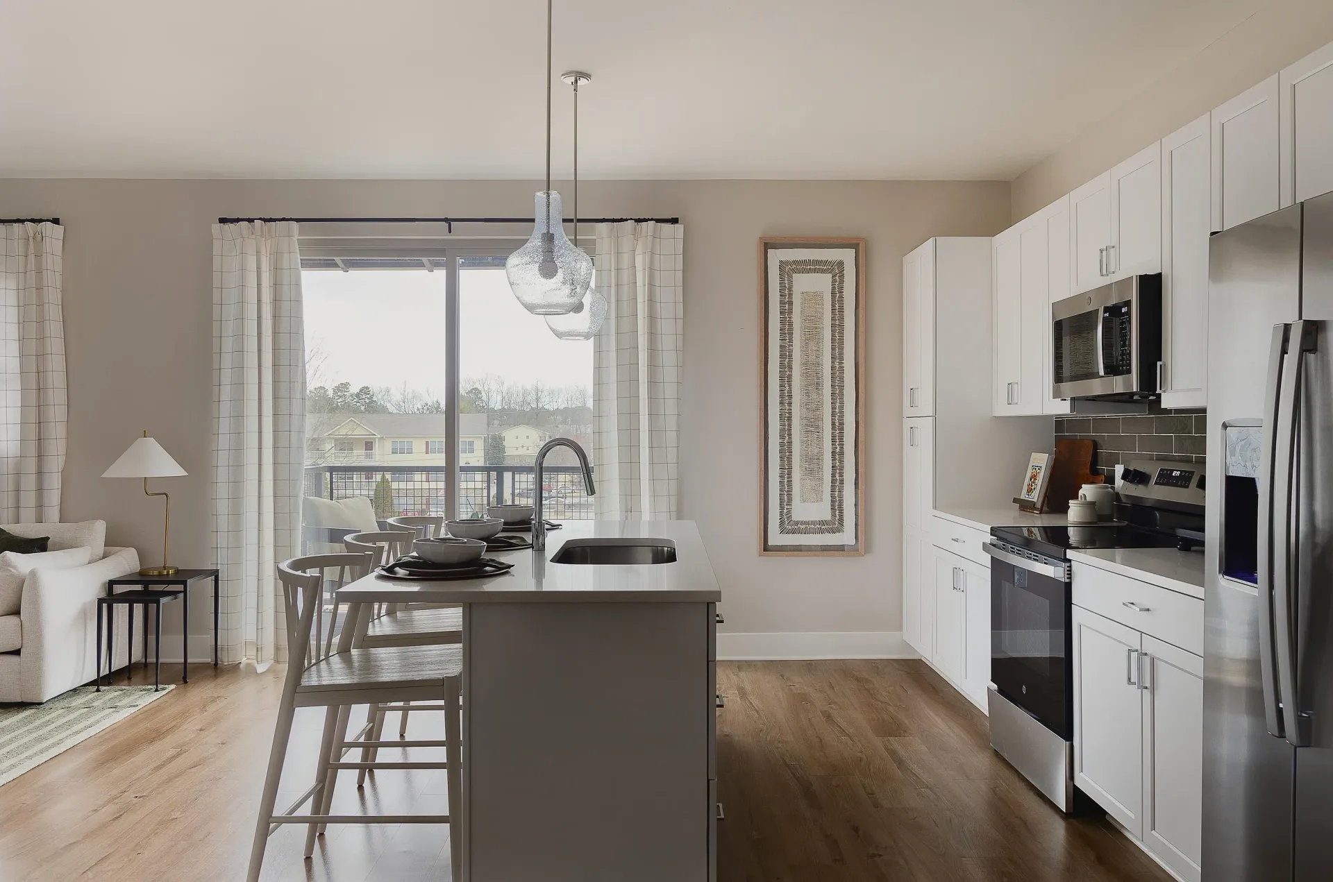 Modern kitchen with island, stainless steel appliances, and balcony access.