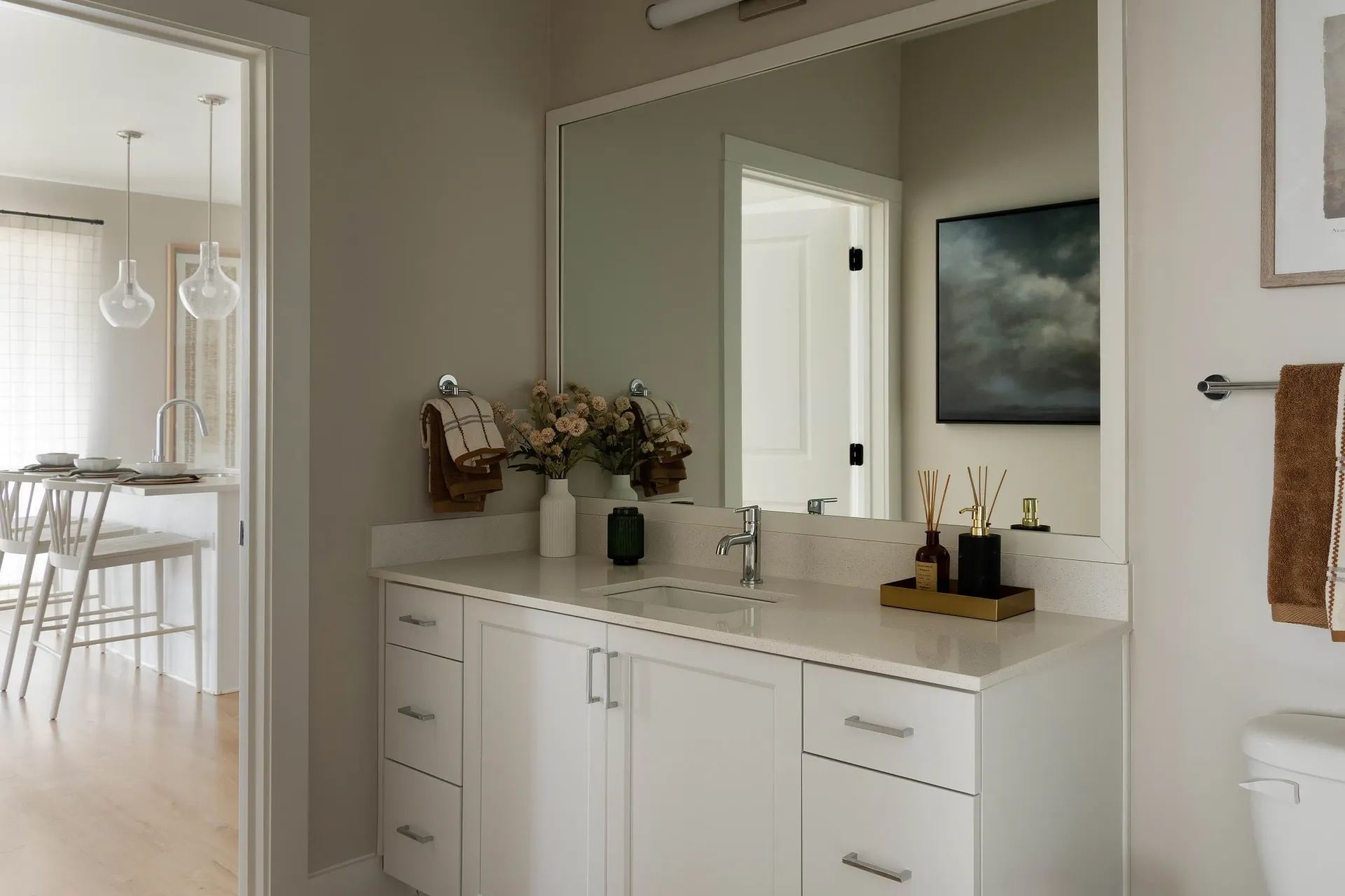 Modern bathroom vanity with a large mirror, white countertops, and ample storage.